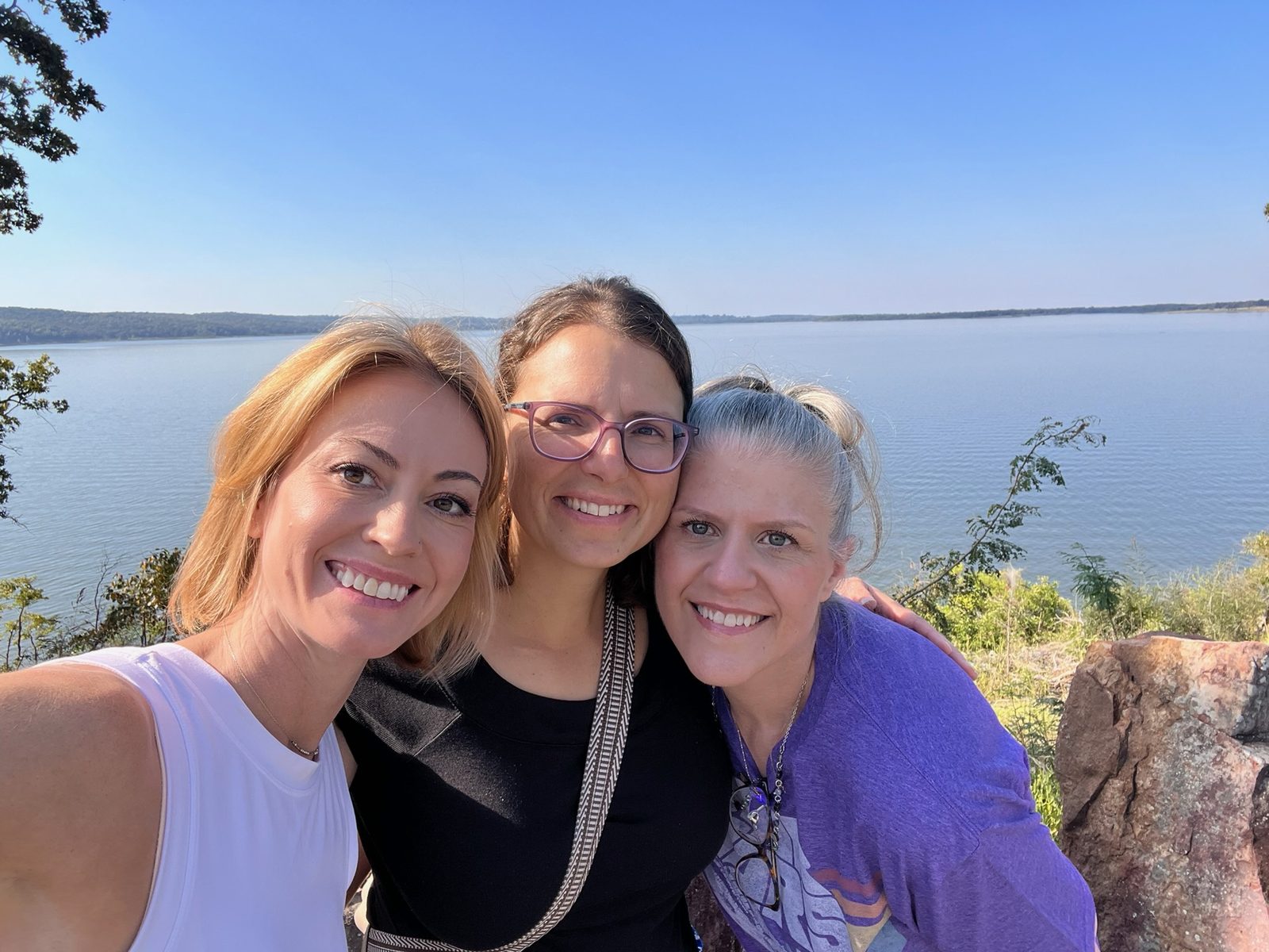 Three retreat attendees smiling together at the lake